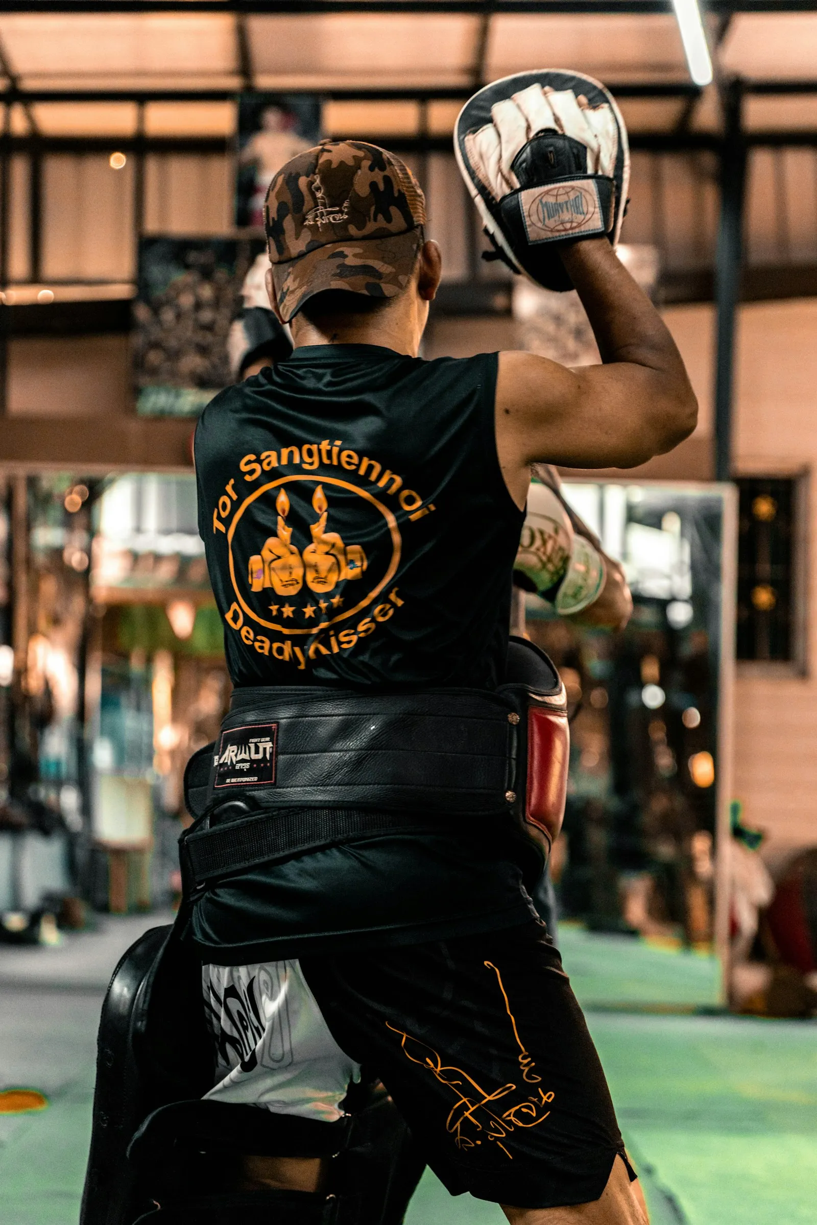 Alumno entrenando golpes con pads junto al instructor